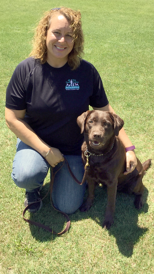 Our Senior Trainer, Cori Mitchell, poses with a brown dog named Ziva.